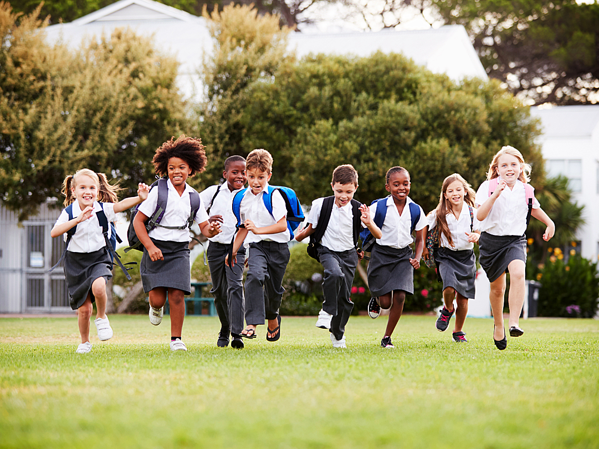 Group of kids in private school uniforms running outside toward camera for article Top 25 largest private schools in Austin for newcomers moving to Austin.