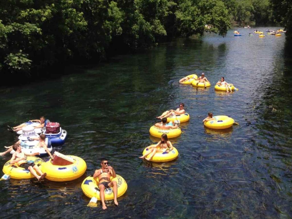 People tubing down San Marcos river in yellow tubes for article Best Tubing Trips Near Austin for newcomers moving to Austin.