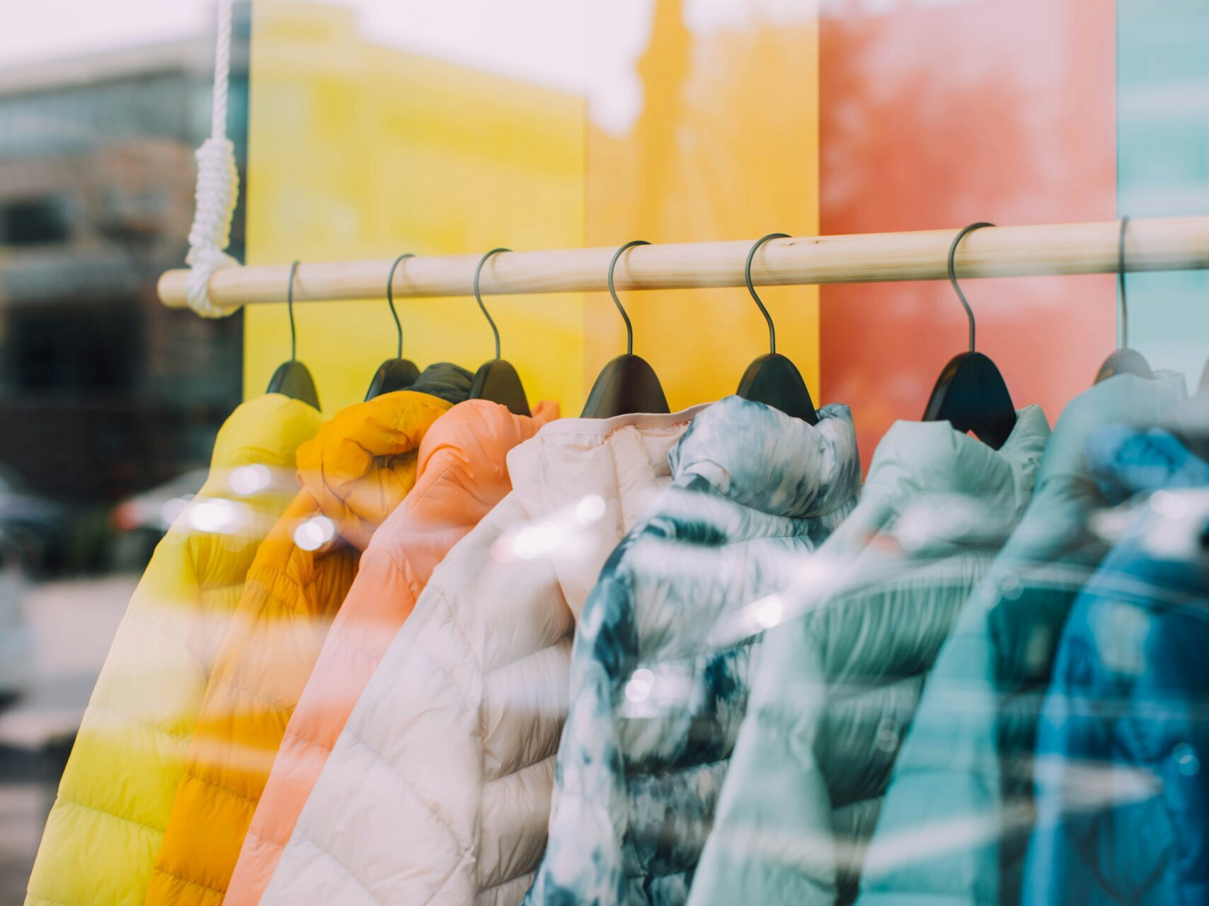 colorful coats through a window of a retail store