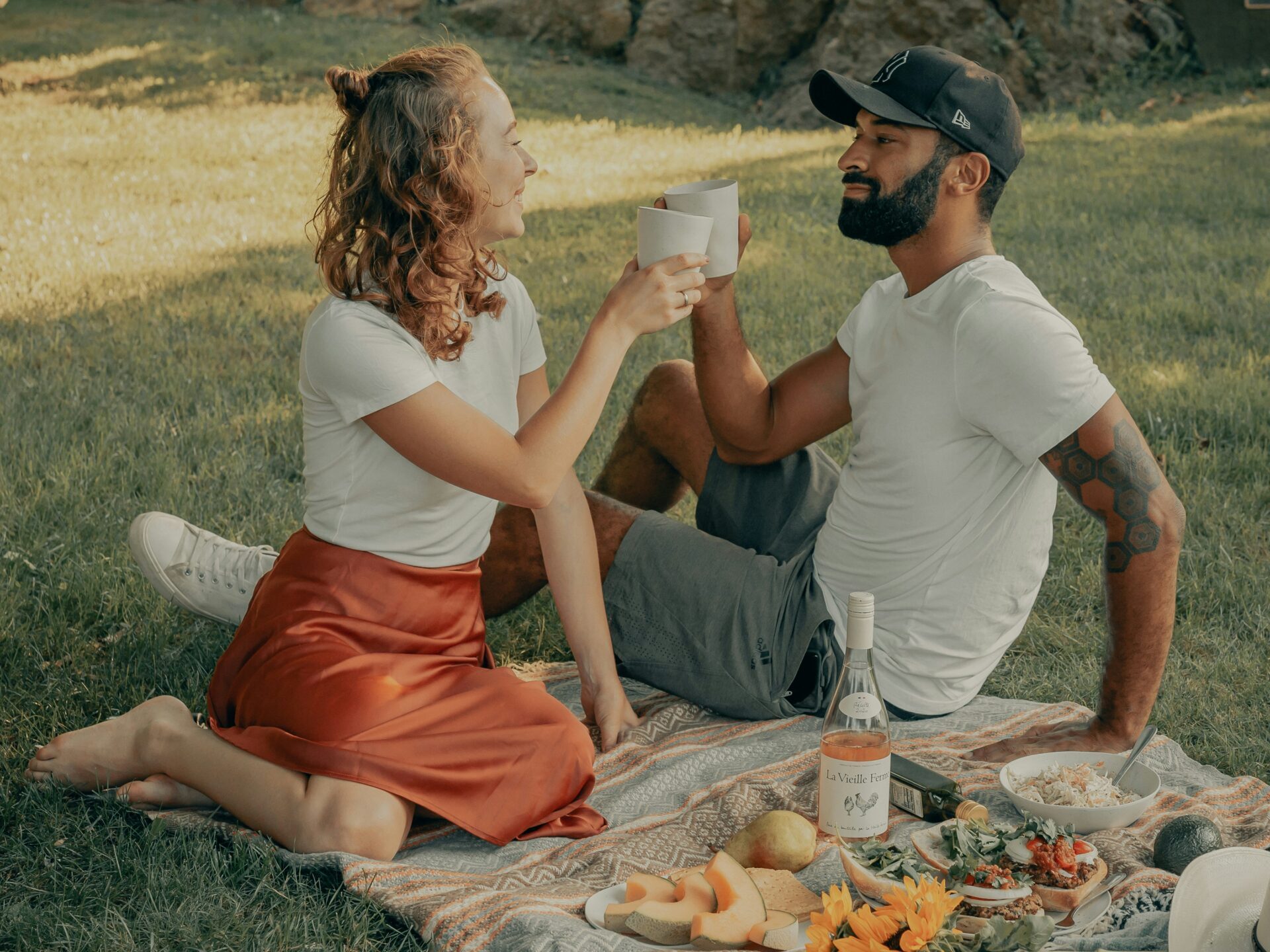 couple toasting wine on picnic blanket at park