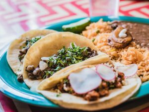 plate of tacos, rice and beans on a bright blue plate