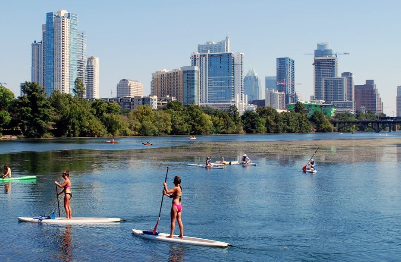 people on paddle boards in the lake viewing the Austin skyline
