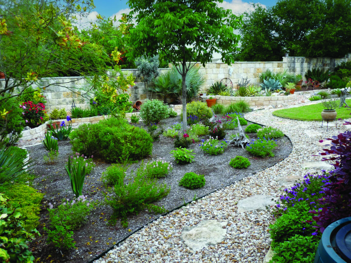 Patio with plants surrounding it with a pathway of rocks