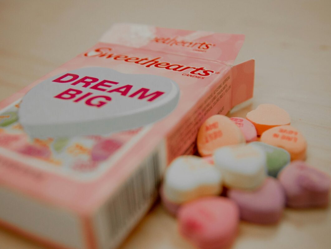 a box of Sweetheart candies and some beside the box on a table
