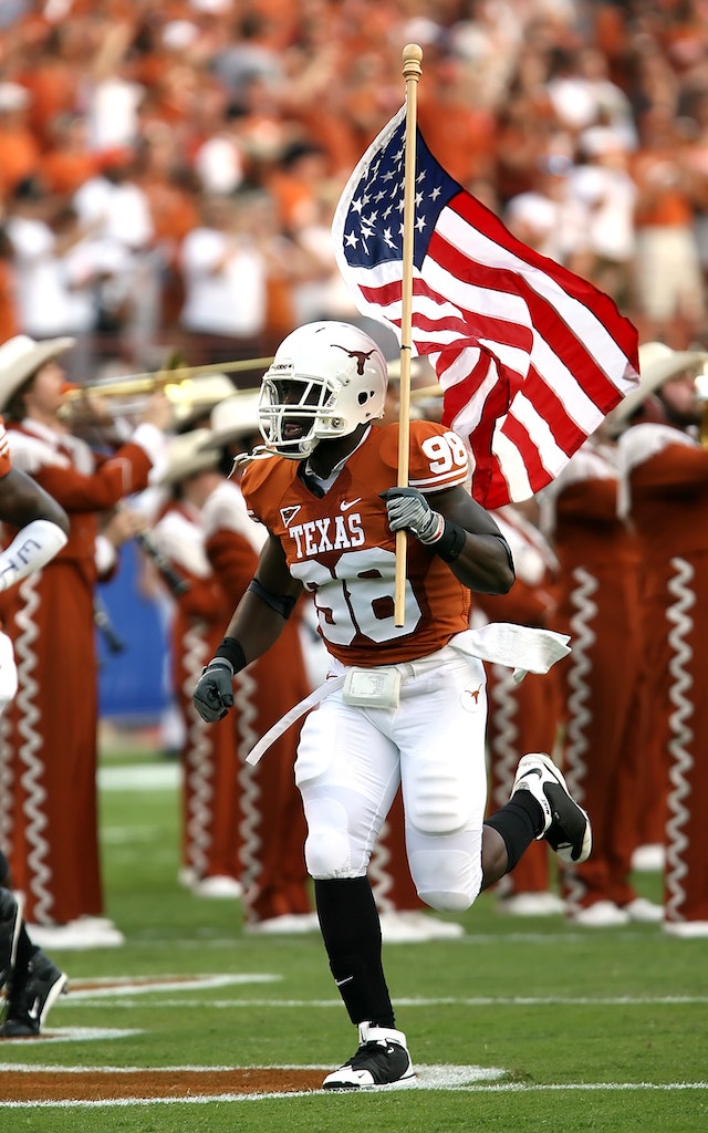 UT Longhorn football player Holding a USA Flag and running on the field.