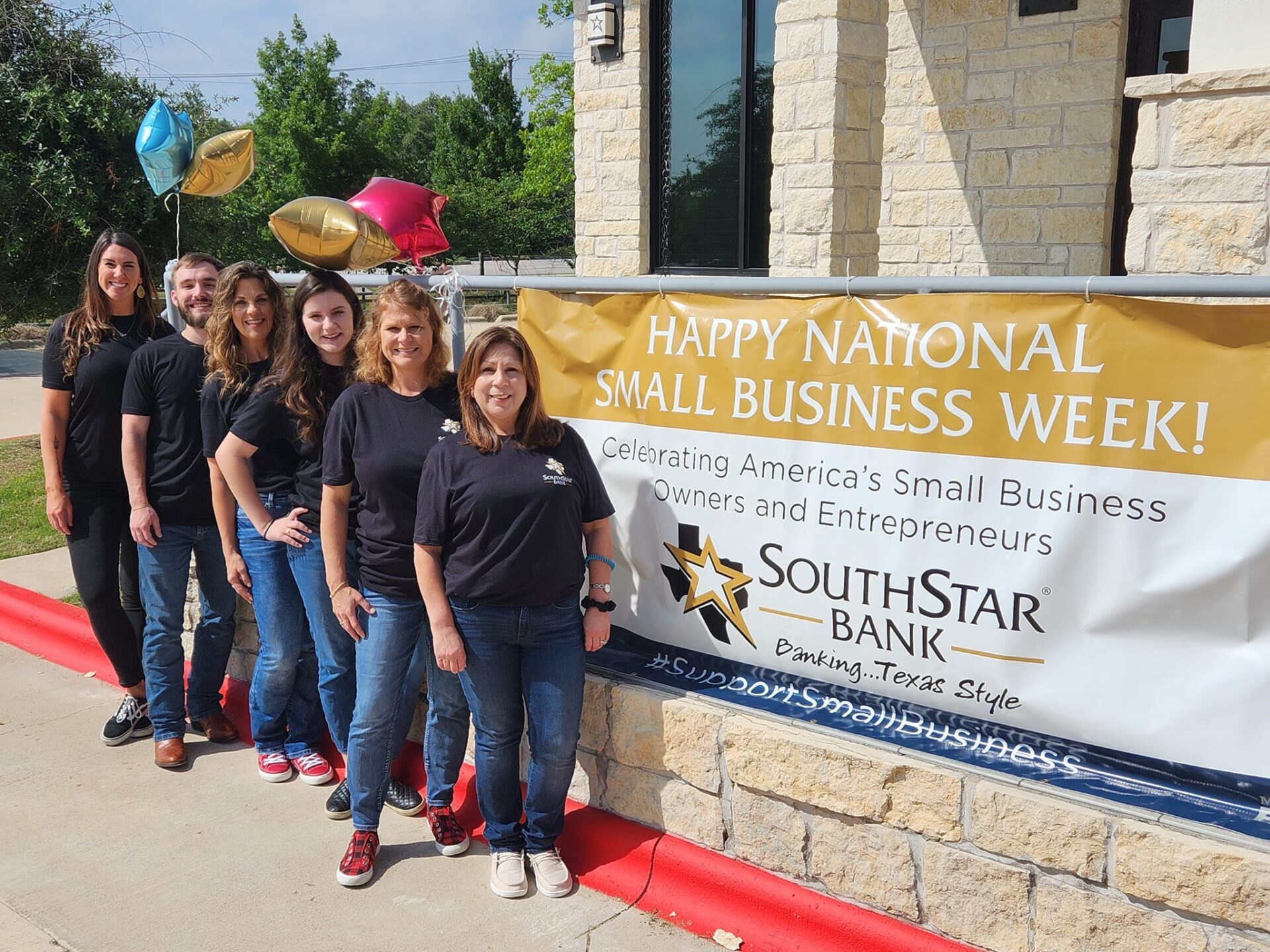 group of SouthStar Bank employees wearing black shirts and jeans in front of a sign