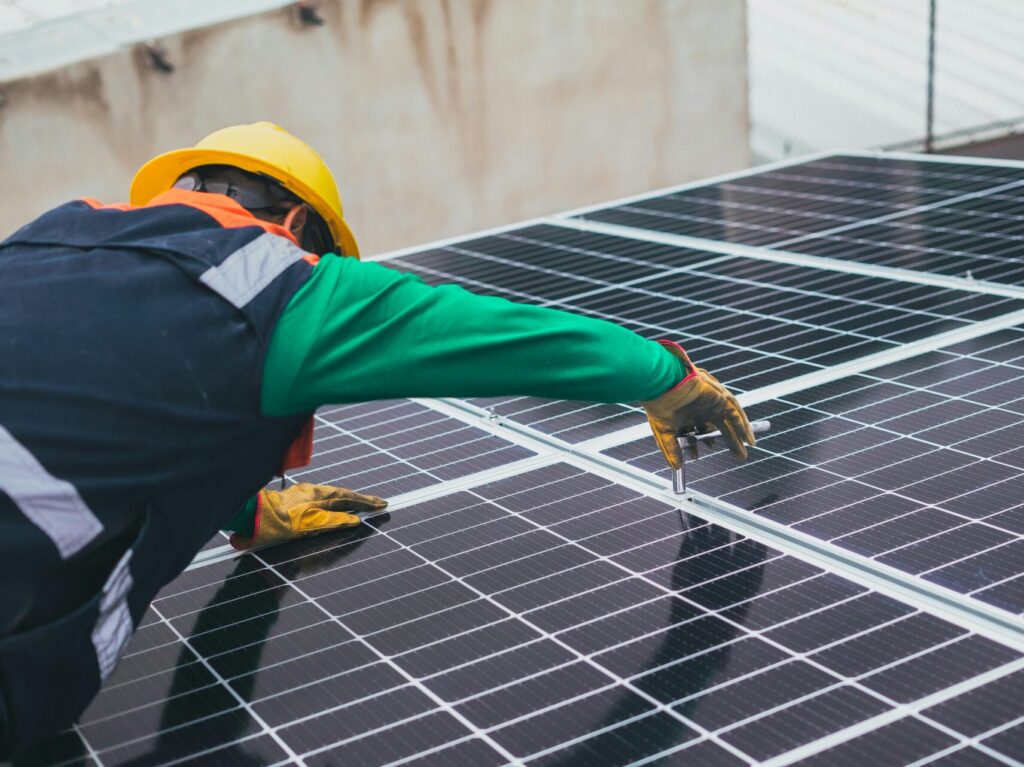 man in green shirt and yellow hard hat installing solar panels