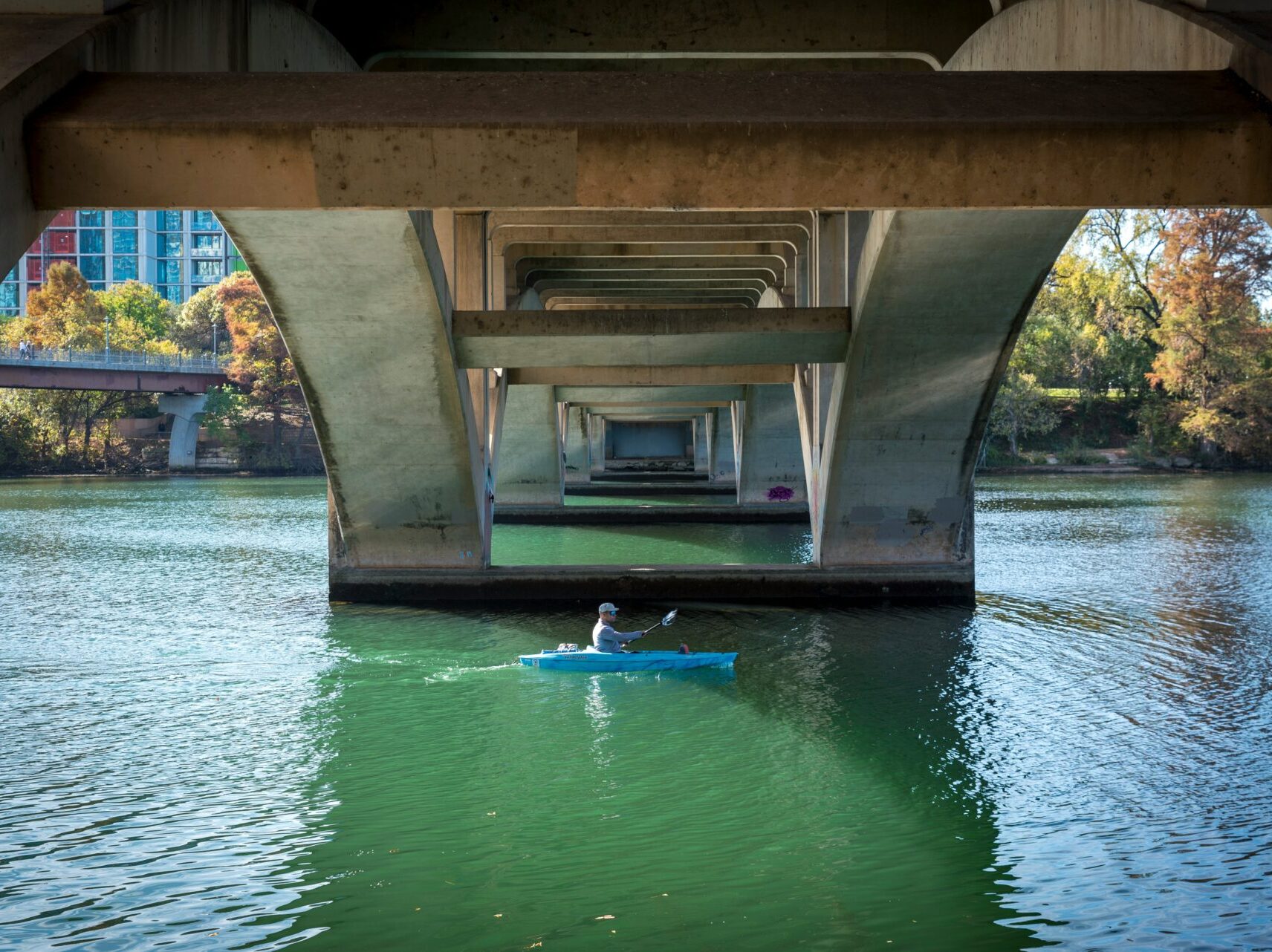man kayaking under bridge on Lady Bird Lake in Austin