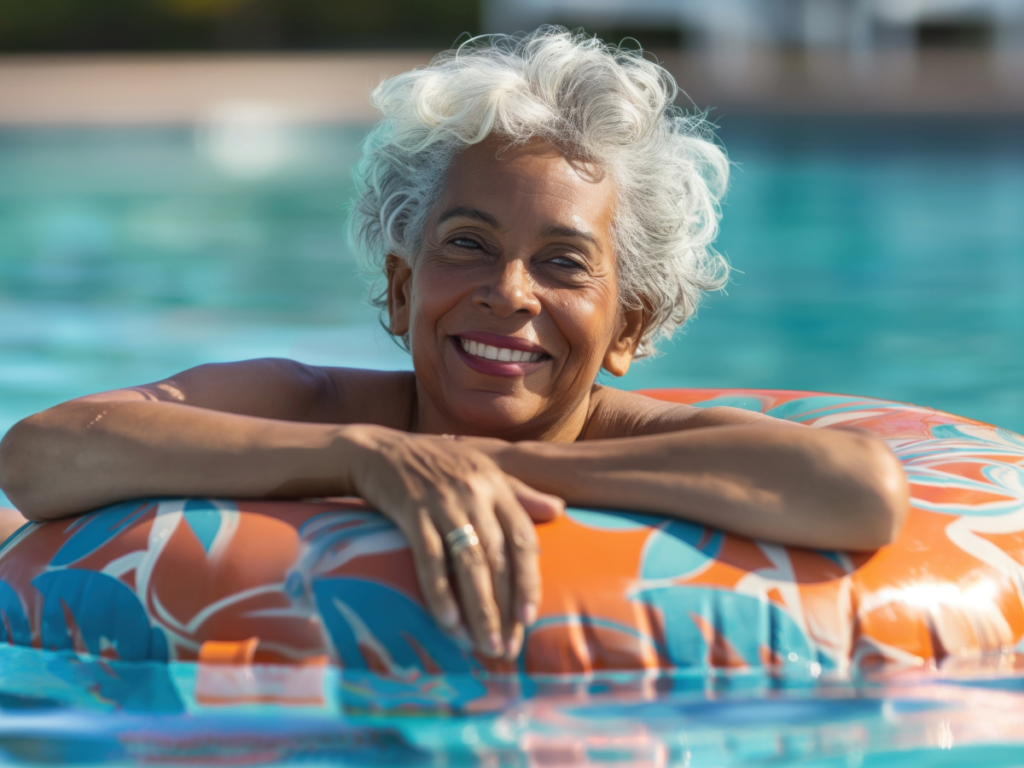 Senior woman smiling in pool with arms resting on floating raft.