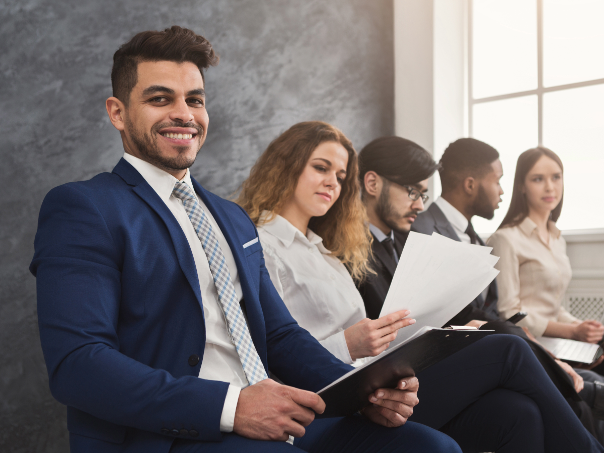 Row of young people sitting with resume in hand waiting to get called for job interview.