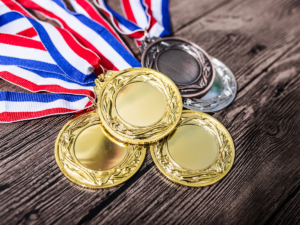 1st, 2nd, 3rd place medals stacked on table with red, white and blue ribbons attached.