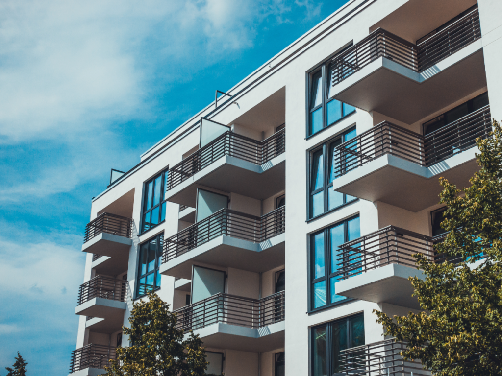 Looking up at corner of modern apartment building with balconies.