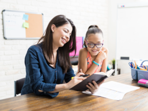 Woman tutoring girl at a desk.