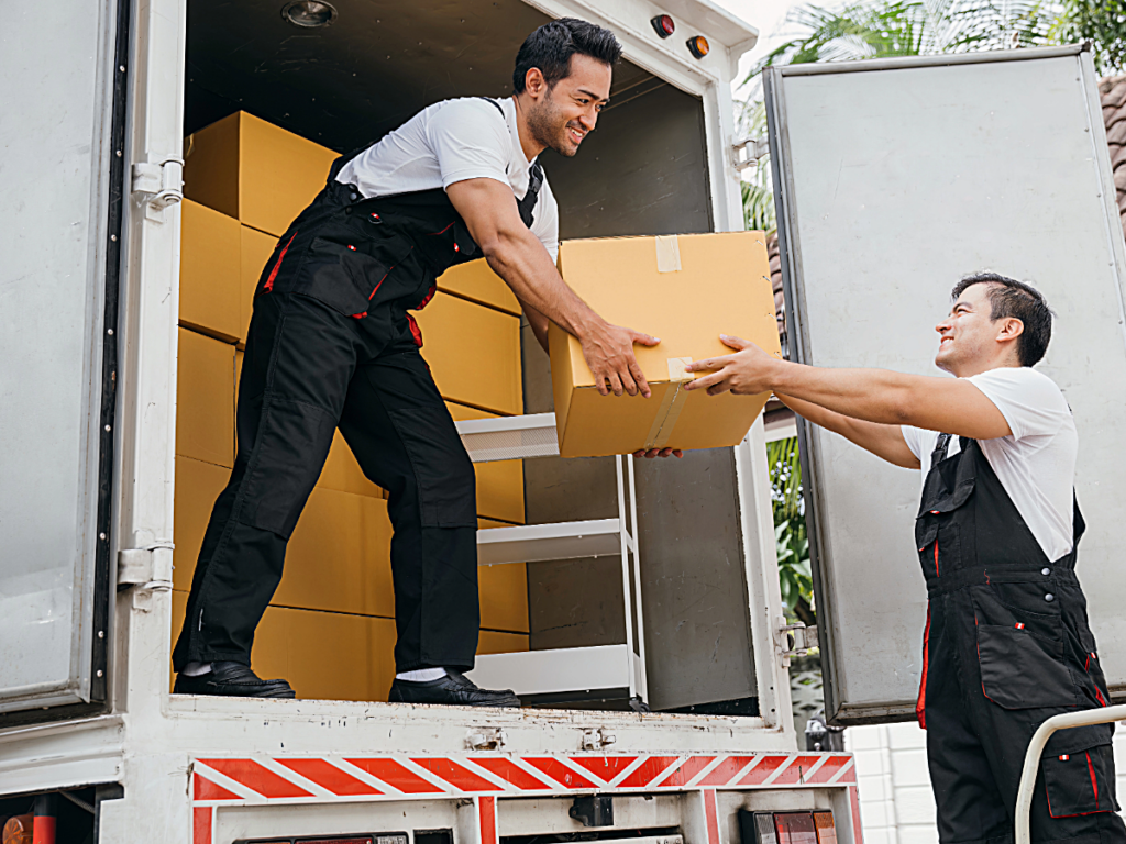 Professional movers moving boxes out of moving truck.