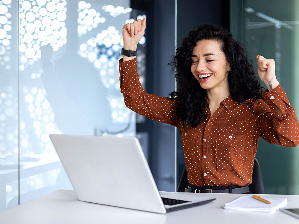 Person celebrating in front of computer after finding contract work online.