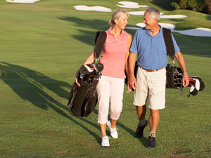 Senior couple carrying their golf bags walking out on a golf course. For article - Top 5 Golf Courses in Austin.