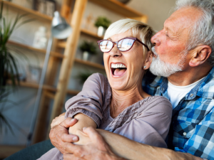 Senior couple embracing with mans arms wrapped around his wife in their home for article Retire in Austin: 9 Most Desirable Places for newcomers moving to Austin.