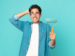 Man holding roller with whoops look on his face for article 7 Costly Painting Mistakes to Avoid.