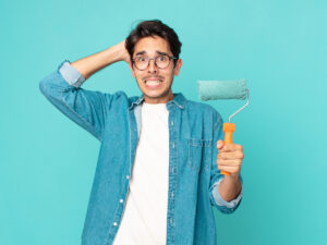 Man holding roller with whoops look on his face for article 7 Costly Painting Mistakes to Avoid for newcomers moving to Austin.