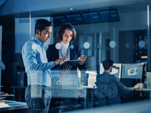 Male and female IT coworkers looking over a laptop in a technology office for article 10 Leading Technology Companies in Austin for newcomers moving to Austin.