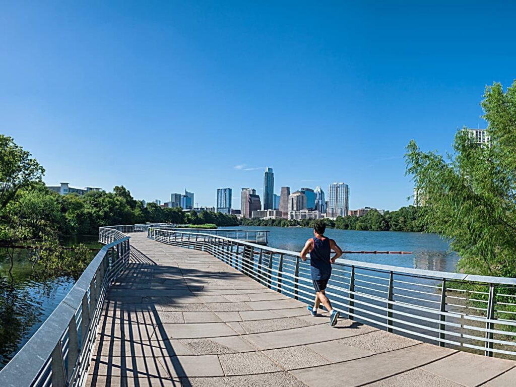 Person jogging away from camera on trail going over part of Lady Bird Lake for article Austin's Hottest Zip Code: 78704 for newcomers moving to Austin.