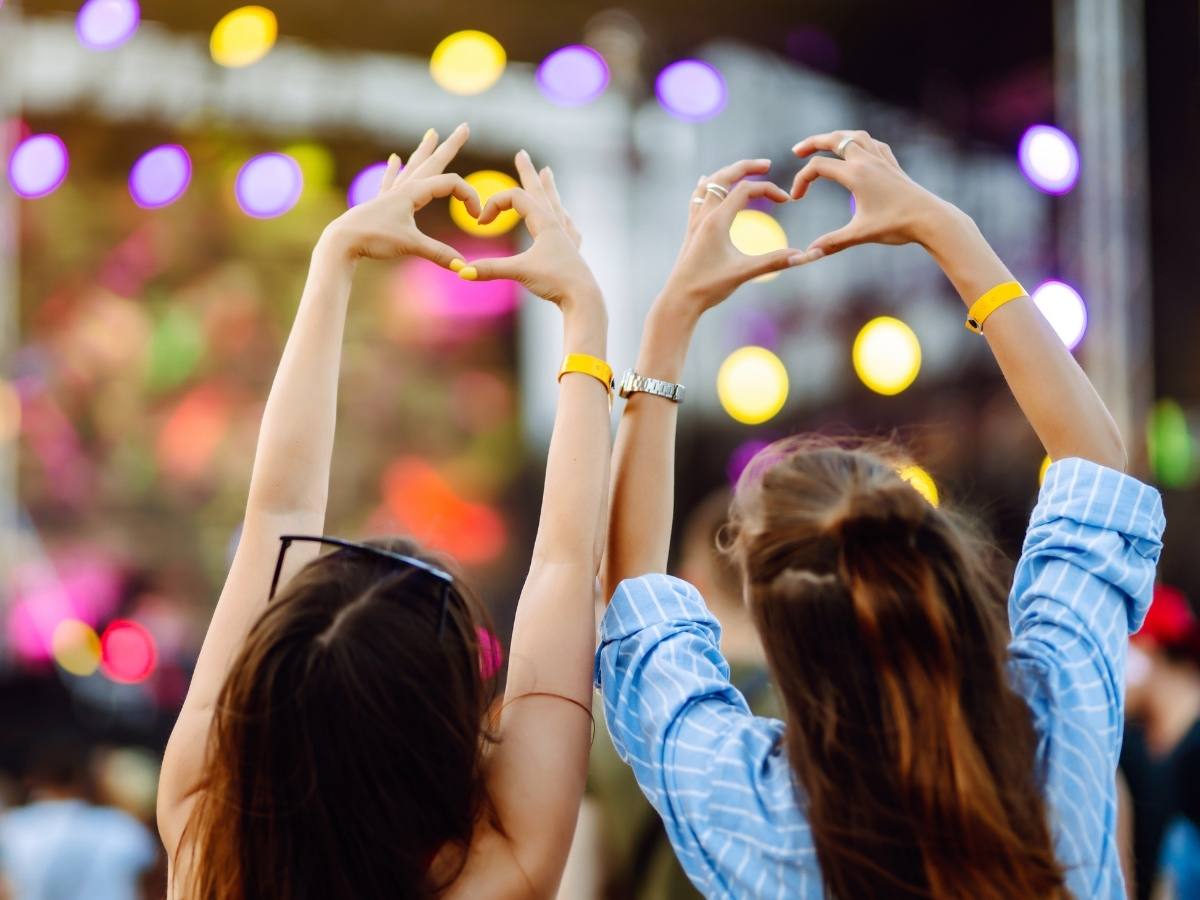 Heart shaped hands at concert. Music concert with lights and silhouette of people enjoying concert for article March Events in Austin for newcomers moving to Austin.