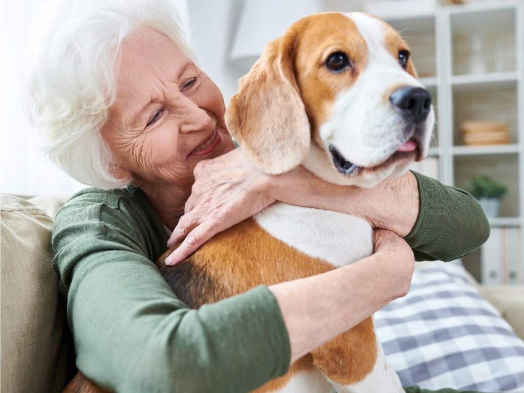 Senior woman sitting on couch with arms wrapped around dog for article Pet-Friendly Senior Living in Austin for newcomers retiring in Austin.