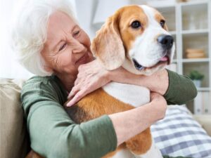 Senior woman sitting on couch with arms wrapped around dog for article Pet-Friendly Senior Living in Austin for newcomers retiring in Austin.