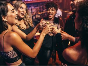 People out in a club toasting with cocktails for article Nightlife in Austin: 21 Can't-Miss Spots for Newcomers moving o Austin.