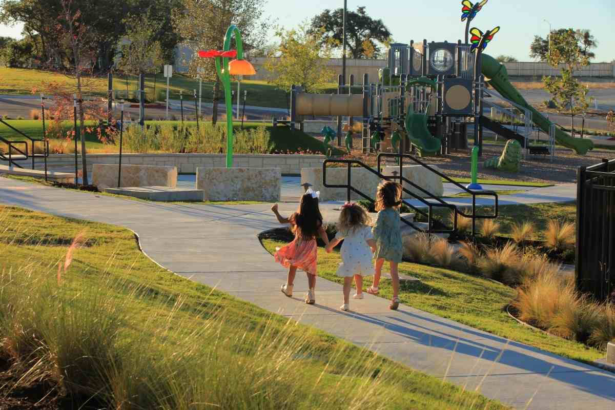 3 girls skipping on path to playground for article Nolina — Where Life Blossoms for newcomers moving to Austin.