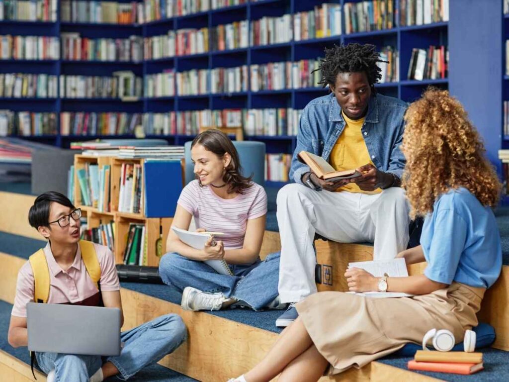 Group of students sitting around library with books and laps for article 7 Powerful Reasons to Get a Library Card in Austin for newcomers moving to Austin.