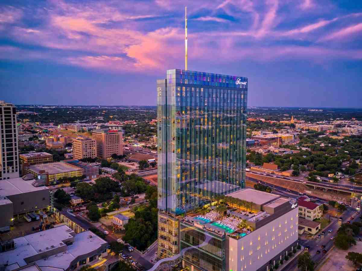 Aerial view of the hotel with pink and purple sky for article Fairmont Austin: A Hotel on a Park Perfect for Newcomers and Visitors moving to Austin or moving to the Austin area.