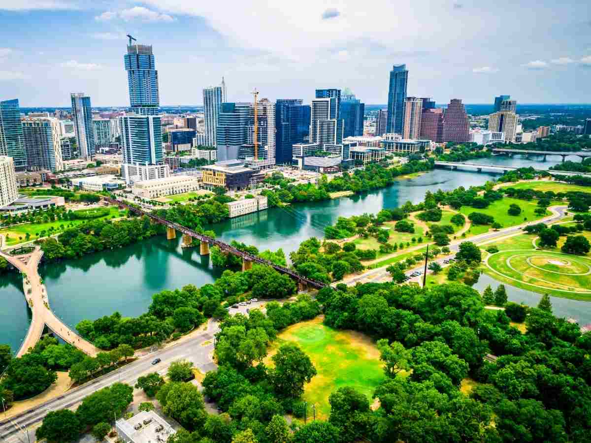 Skyline of city of Austin in background with river and green parks in foreground for article Austin Ranked Among Top 5 Boomtown Cities for newcomers moving to Austin or moving within Austin.