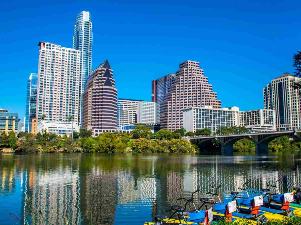 Lady Bird Lake with downtown Austin in the background and paddle bicycles in the foreground for article Austin Area Lakes Overview for newcomers moving to Austin.